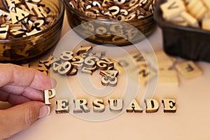 Hand woman forming persuade text with small wooden letters and holding letter P