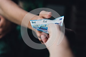 Hand of woman is giving euro money to a young man