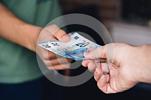 Hand of woman is giving euro money to a young man