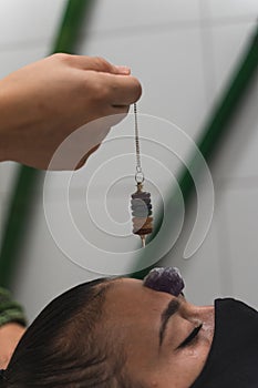 Hand of a woman healer applying reiki and energy therapies through the use of a pendulum