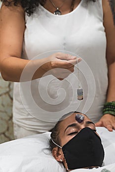 Hand of a woman healer applying reiki and energy therapies through the use of a pendulum