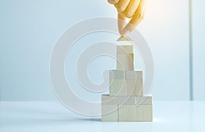 Hand woman holding block wood stack house model on white background,Real estate growth up concept