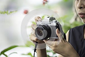 Hand woman holding the camera Taking pictures Background blurry trees