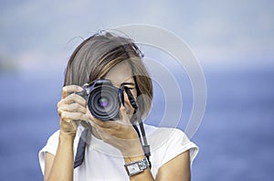 Hand woman holding the camera Taking pictures background Kaeng Krachan dam phetchaburi , Thailand