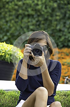 Hand woman holding the camera Taking pictures Background of trees and flowers