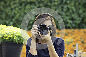 Hand woman holding the camera Taking pictures Background of trees and flowers