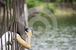 Hand woman holding the camera Taking pictures on wooden bridge Background Kaeng Krachan dam phetchaburi , Thailand