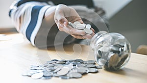 In the hand of a woman holding a coin or money and put it into the piggy bank, Saving money for future use, saving money