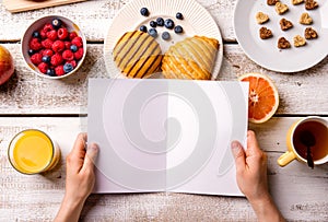 Hand of woman holding empty greeting card. Breakfast meal.