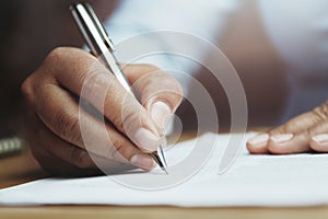 hand of woman holding pen with writing on paper report