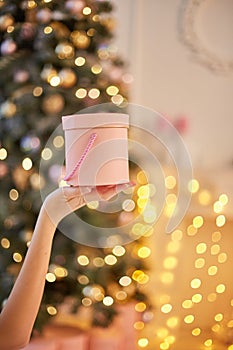 Hand woman holding pink gift box for new year on Christmas background with space.