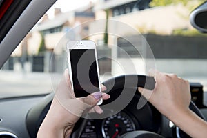 Hand of woman holding steering wheel and mobile phone driving car while texting distracted in risk