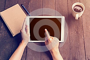 Hand woman holding tablet working on wood table in coffee shop with vintage filter.