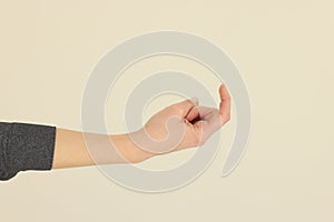 Hand of woman making beckoning sign on beige background