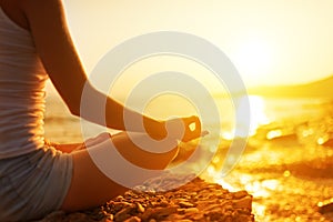 Hand of woman meditating in a yoga pose on beach photo