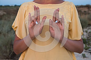 Hand of a woman meditating in a yoga pose on the beach at sunset