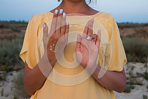 Hand of a woman meditating in a yoga pose on the beach at sunset