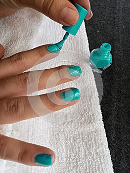 hand of woman painting her nails in aquamarine color photo