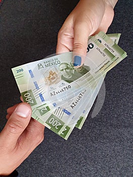 hand of a woman paying with Mexican money and hand of a  man receiving