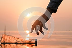 Hand Woman picking up empty of plastic bottle cleaning on the beach , volunteer concept. Environmental pollution.