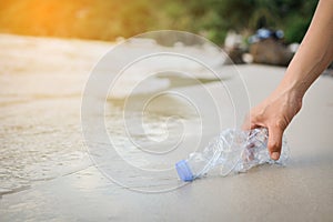 Hand woman picking up plastic bottle cleaning on the beach