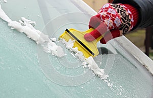 Hand of woman scraping ice from car windscreen