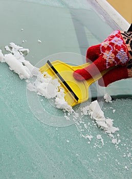 Hand of woman scraping ice from car windscreen