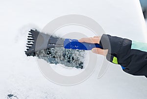 Hand of a woman Scraping snow and ice from the car windscreen