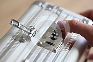 Hand of woman setting up password to unlock silver briefcase