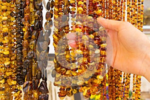 Hand of woman with shiny womanly amber necklaces on stall at the bazaar
