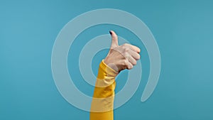Hand of woman showing thumb up sign on blue background. Positive young girl. Like. Success. Body language.