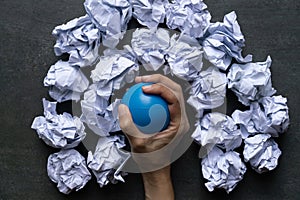 Hand of a woman squeezing a stress ball with crumpled paper