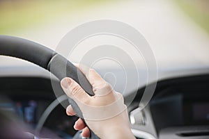 Hand of woman on steering wheel inside car