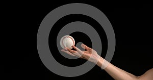 Hand of Woman Throwing a Ball of Baseball against Black Background