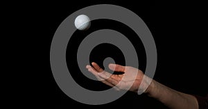 Hand of Woman Throwing a Ball of Golf against Black Background