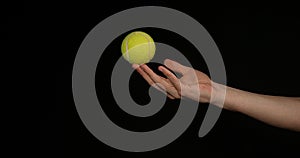 Hand of Woman Throwing a Ball of tennis against Black Background