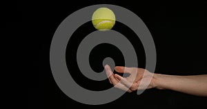 Hand of Woman Throwing a Ball of tennis against Black Background