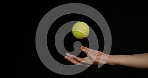 Hand of Woman Throwing a Ball of tennis against Black Background