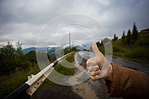 Hand of woman traveler with thumbs up on asphalt road go to travel