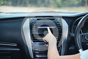 Hand of woman turning on car air condition system,Button on dashboard in car panel,Auto car air condition Car dashboard. Radio