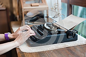 Hand of woman typing on old vintage typewriter with paper