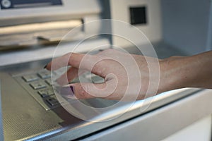 Hand of woman typing security code on cash machine.