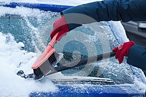 Hand of woman using brush and remove snow from car and windscreen