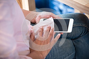 Hand of woman using shirt to clean smart phone screen technology lifestyle concept