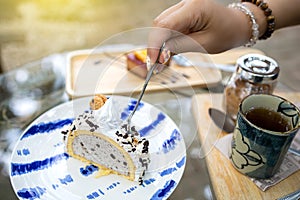 The hand of a woman using a spoon to scoop ice cream cake