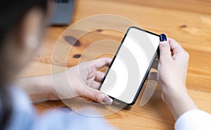 hand woman using a telephone, empty screen smart phone and computer on wooden table top view.