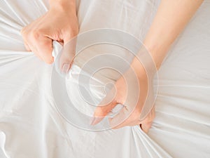 Hand of women pulling white sheets in lust and orgasm.