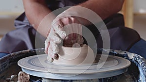 Hand work on pottery wheel, shaping a clay pot, student make of clay pot at studio