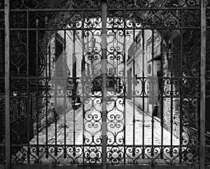 Hand-worked wrought iron gate with internal courtyard of an old