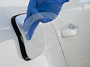 The hand of a worker in a blue glove closes the hatch of the gas tank of the car